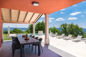 un patio al aire libre con mesa de madera y sillas en Rainis Hill Top Villa, en Oprtalj