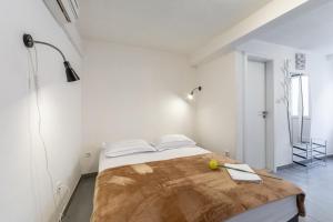 a white bedroom with a bed with a wooden table at Apartments Sonja in Pučišća