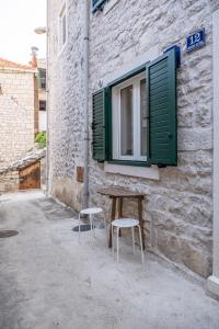 a table and two stools next to a building with a window at Apartments Sonja in Pučišća