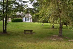un banc dans un parc arboré et une maison dans l'établissement Maison calme avec grand jardin en Sologne, à Chaumont-sur-Tharonne