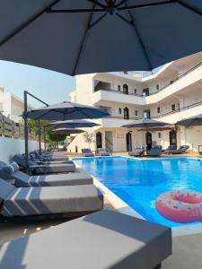 a swimming pool with chairs and umbrellas and a hotel at Penélope Hotel in Ialyssos