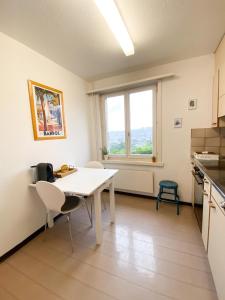 eine Küche mit einem weißen Tisch und Stühlen sowie einem Fenster in der Unterkunft NEB-THUN LODGE`s Appartement 1 Hilterfingen Ringstrasse 6 in Thun