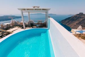 a swimming pool with chairs and the view of the ocean at Kafieris View in Firostefani