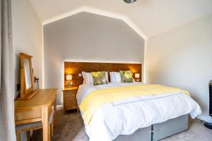 een slaapkamer met een groot bed en een houten bureau bij Brecks Farm - The Tractor Shed in York