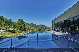 a swimming pool at a resort with mountains in the background at Hotel Sitno Forest Resort - Family friendly in Banská Štiavnica