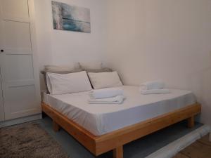 ein Bett mit weißen Laken und weißen Kissen in der Unterkunft STUDIO PORTO in Korfu-Stadt
