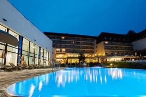 a large swimming pool in front of a building at Hotel Sitno Forest Resort in Vyhne