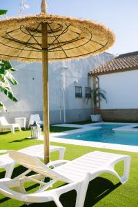 a straw umbrella and two lounge chairs next to a pool at Casa rural El Olivo de Córdoba in Córdoba