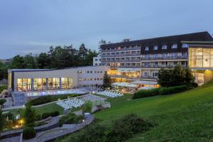 a large building with a courtyard with white tables at Hotel Sitno Forest Resort in Vyhne