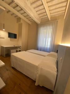 a bedroom with a large white bed and a desk at Albergo Roma in Buonconvento
