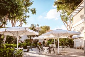 an outdoor patio with tables and umbrellas at Kfar Maccabiah Business & Sport Hotel in Ramat Gan