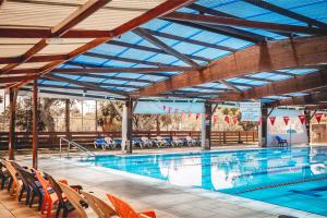 a large swimming pool with chairs around it at Kfar Maccabiah Business & Sport Hotel in Ramat Gan
