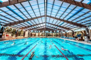 a group of people swimming in a swimming pool at Kfar Maccabiah Business & Sport Hotel in Ramat Gan