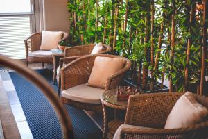 a room with wicker chairs and tables and plants at Kfar Maccabiah Business & Sport Hotel in Ramat Gan