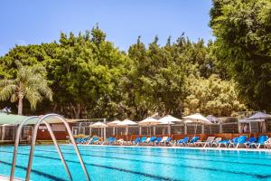 a swimming pool with chairs and umbrellas at Kfar Maccabiah Business & Sport Hotel in Ramat Gan
