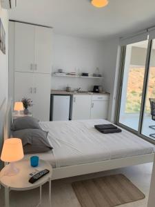 a white bedroom with a large bed and a table at Caldera Blue in Alikí