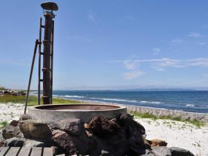 a fire pit on the beach next to the ocean at Pension Arumeria in Wakkanai