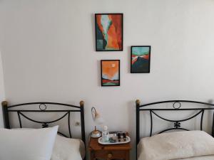2 Betten in einem Schlafzimmer mit 3 Bildern an der Wand in der Unterkunft Fotini & Dimitrios in Fri