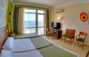 
a hotel room with a bed, chair, table and television at Hotel & Spa Entremares in La Manga del Mar Menor
