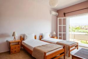 two beds in a room with a window at Rena's Hospitality walk to the beach,10min to Chania! in Kato Daratso