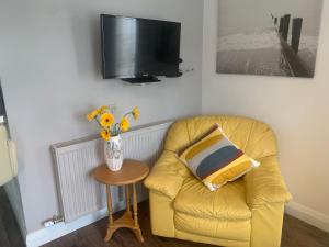 a living room with a yellow chair and a tv at Hillcrest House Self Catering Apartments in Donegal
