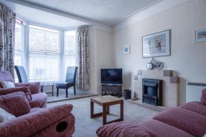 a living room with a couch and a fireplace at Dragons Den - 2 Bedroom Apartment - Tenby in Tenby