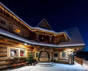 a log cabin in the snow at night at Penzion Damisport in Donovaly