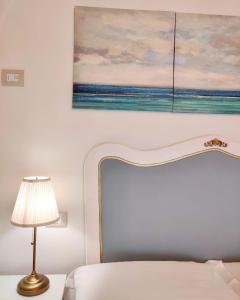ein Schlafzimmer mit einem Gemälde über einem Bett mit einer Lampe in der Unterkunft RomAntica in Polignano a Mare
