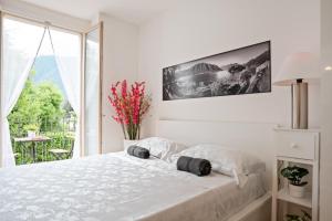 a white bedroom with a large bed and a window at Lake Como Studio with Balcony and Private Parking in Ossuccio