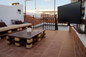 a flat screen tv on a balcony with a coffee table at Apartamento Turístico Almagre in Almagro