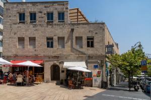 ein altes Gebäude mit Tischen und Sonnenschirmen auf einer Straße in der Unterkunft Shlomtzi Hotel in Jerusalem