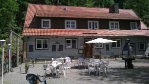 een huis met tafels en stoelen ervoor bij Waldpension Harzer Waldwinkel in Bad Grund
