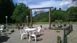 une table et des chaises blanches dans un parc avec un pont dans l'établissement Waldpension Harzer Waldwinkel, à Bad Grund