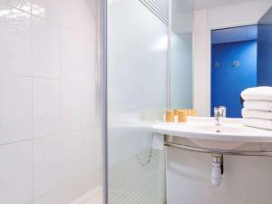 een witte badkamer met een wastafel en een douche bij ibis budget Bayonne in Bayonne