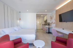 a hotel room with a white bed and red chairs at Aparthotel BCL Levante Beach in Benidorm