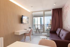 a room with a couch and a table and a balcony at Aparthotel BCL Levante Beach in Benidorm