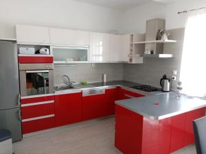 a red kitchen with white cabinets and a sink at Apartman Perkovic in Šibenik +12 photos