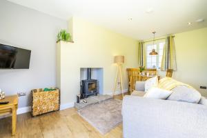 sala de estar con sofá y chimenea en Brecks Farm - Well Cottage en York