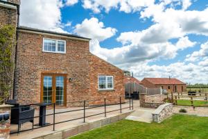 a brick house with a patio and grass yard at Brecks Farm - Well Cottage in York