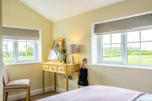 a bedroom with a table and a mirror and two windows at Brecks Farm - Well Cottage in York