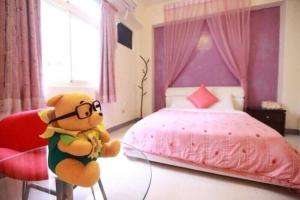 un orsacchiotto in una camera con letto rosa di Hualian Manpo B&B a Città di Hualien Altre 2 foto