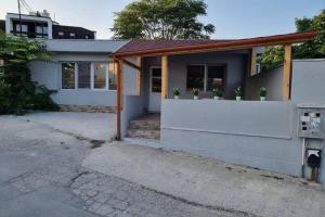 a small white house with a porch with potted plants at Guest House 59 in Varna City