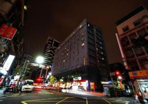 Un palazzo alto in una strada di città di notte di Walker Hotel - Sanchong a Taipei