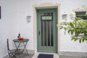 une porte verte menant à un bâtiment blanc avec une table dans l'établissement Villa Adolphine, à Rottach-Egern