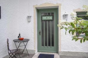 a green door to a white building with a table at Villa Adolphine in Rottach-Egern