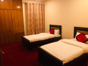 Habitación de hotel con 2 camas con almohadas rojas en Green Guest House Altit Hunza en Hunza