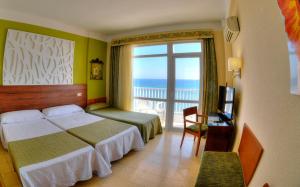 
a bedroom with a bed, chair, and a window at Hotel & Spa Entremares in La Manga del Mar Menor
