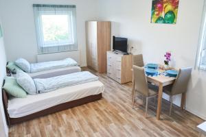 Zimmer mit 3 Betten und einem Tisch mit einem Tisch in der Unterkunft Thermal Apartman - EM in Gárdony