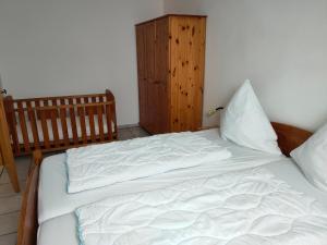 a bed with white sheets and a wooden cabinet at Landsitz Riekenshof in Horumersiel in Wangerland