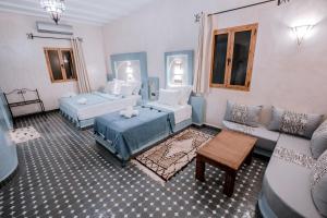 a living room with two beds and a couch at Hassilabiad Appart Hotel in Merzouga